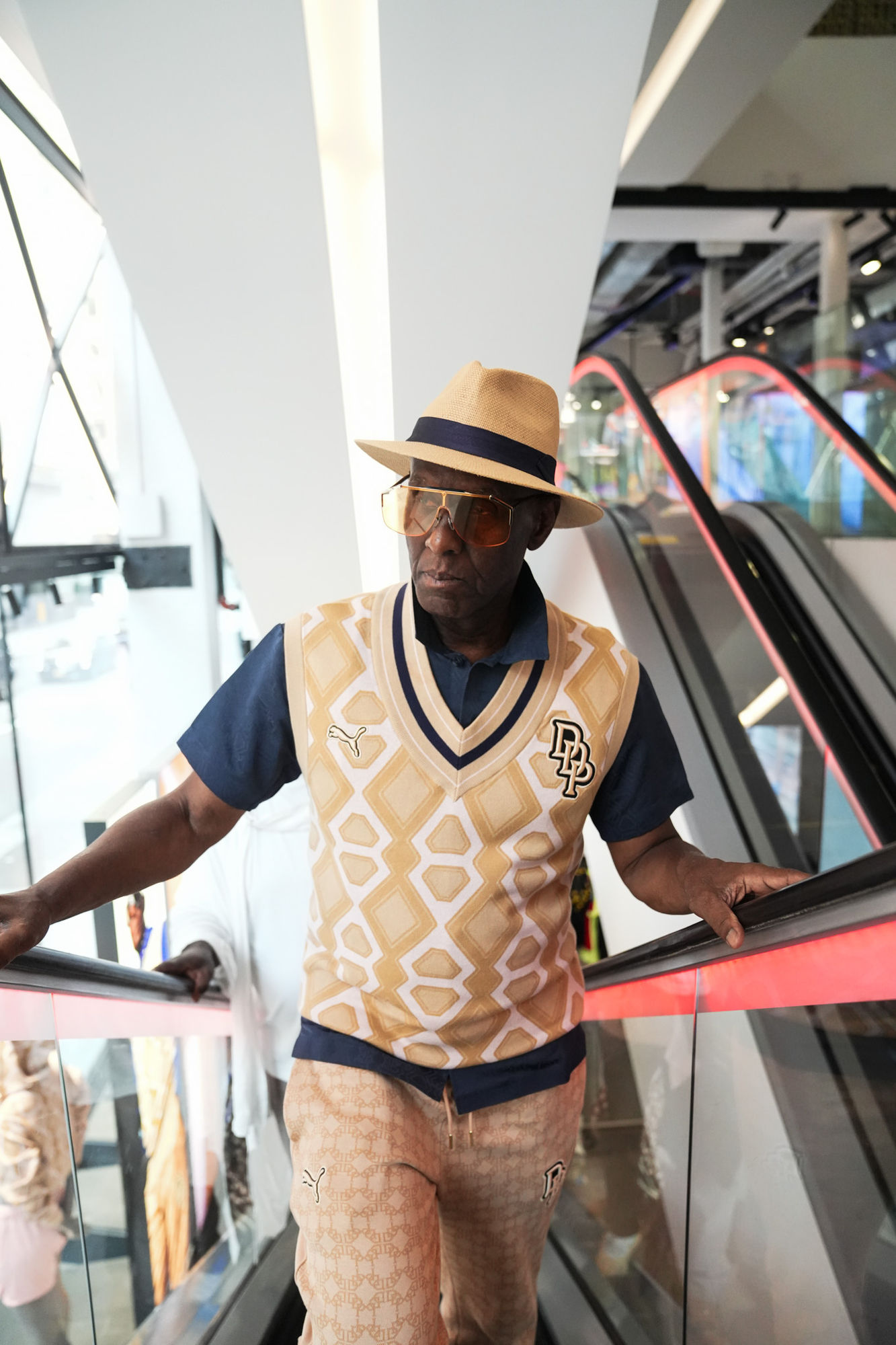 Dapper Dan on an escalator wearing the PUMA × Dapper Dan monogram vest