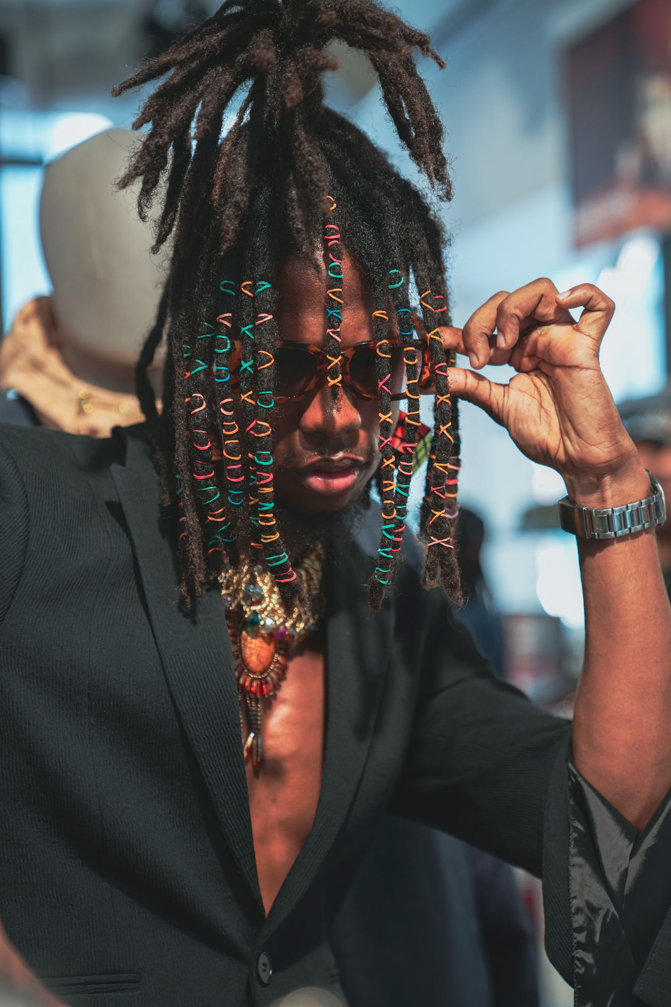 A guest adjusting sunglasses through beaded braids at the PUMA × Dapper Dan launch